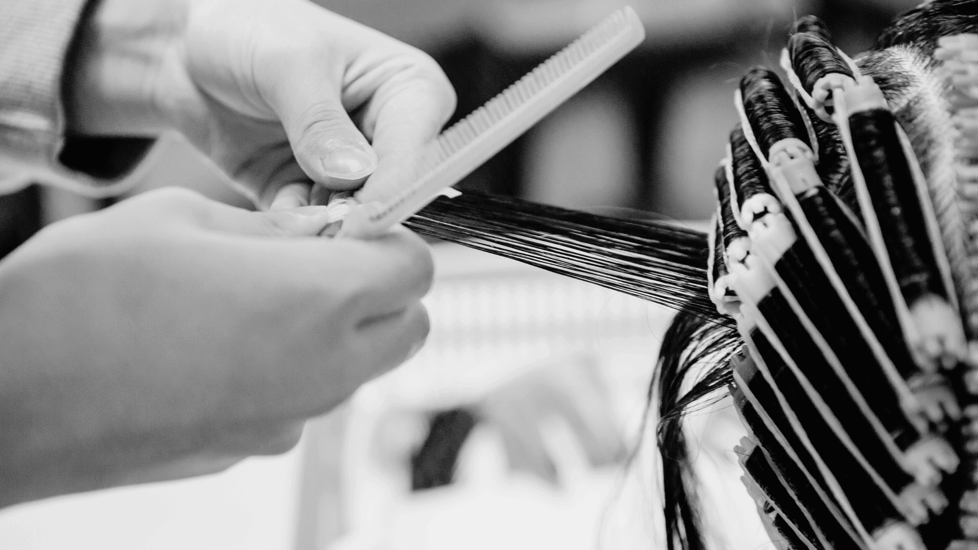 Hands carefully combing and styling hair into curled sections with rollers in a hair salon.