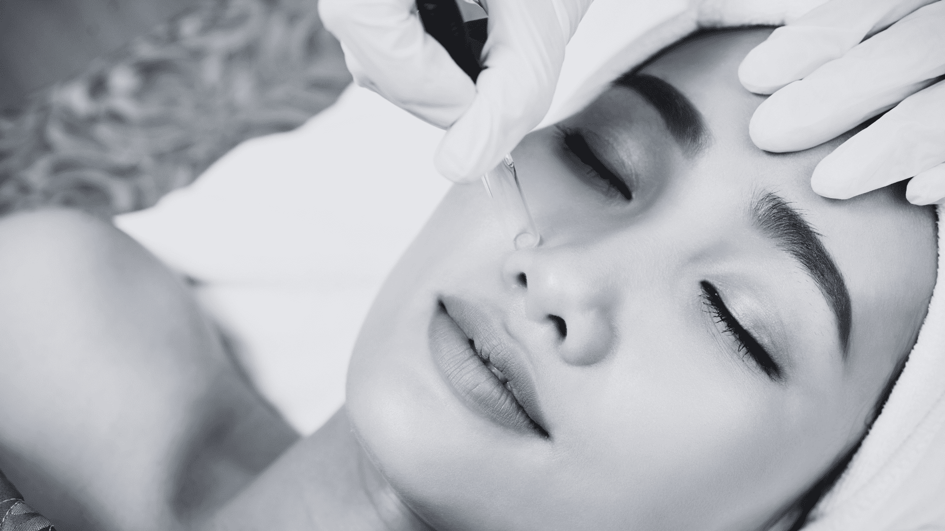 A person receiving a facial skincare treatment with gloves applying a tool to their face.